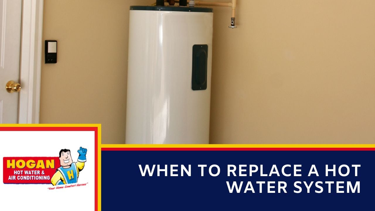 Indoor electric hot water tank positioned near a door, showing valves and pipe connections.