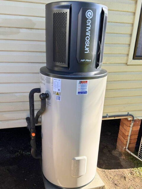 An Envirosun heat pump hot water system unit with Smart Home tech installed outside against house siding.
