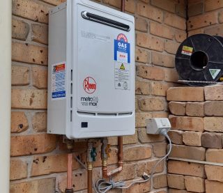 Rheem Metro 26 Max continuous flow gas hot water system delivering 26 litres per minute, installed on a brick wall of a residential home in Newcastle, NSW